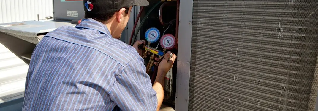 HVAC technician servicing a condenser unit in Batesville